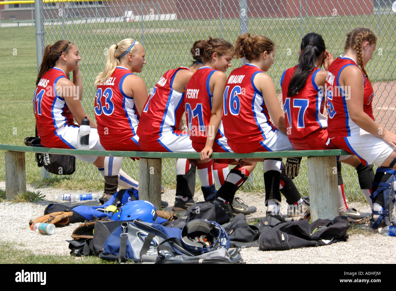 Teenage female Major league Softball players sitting on the bench with