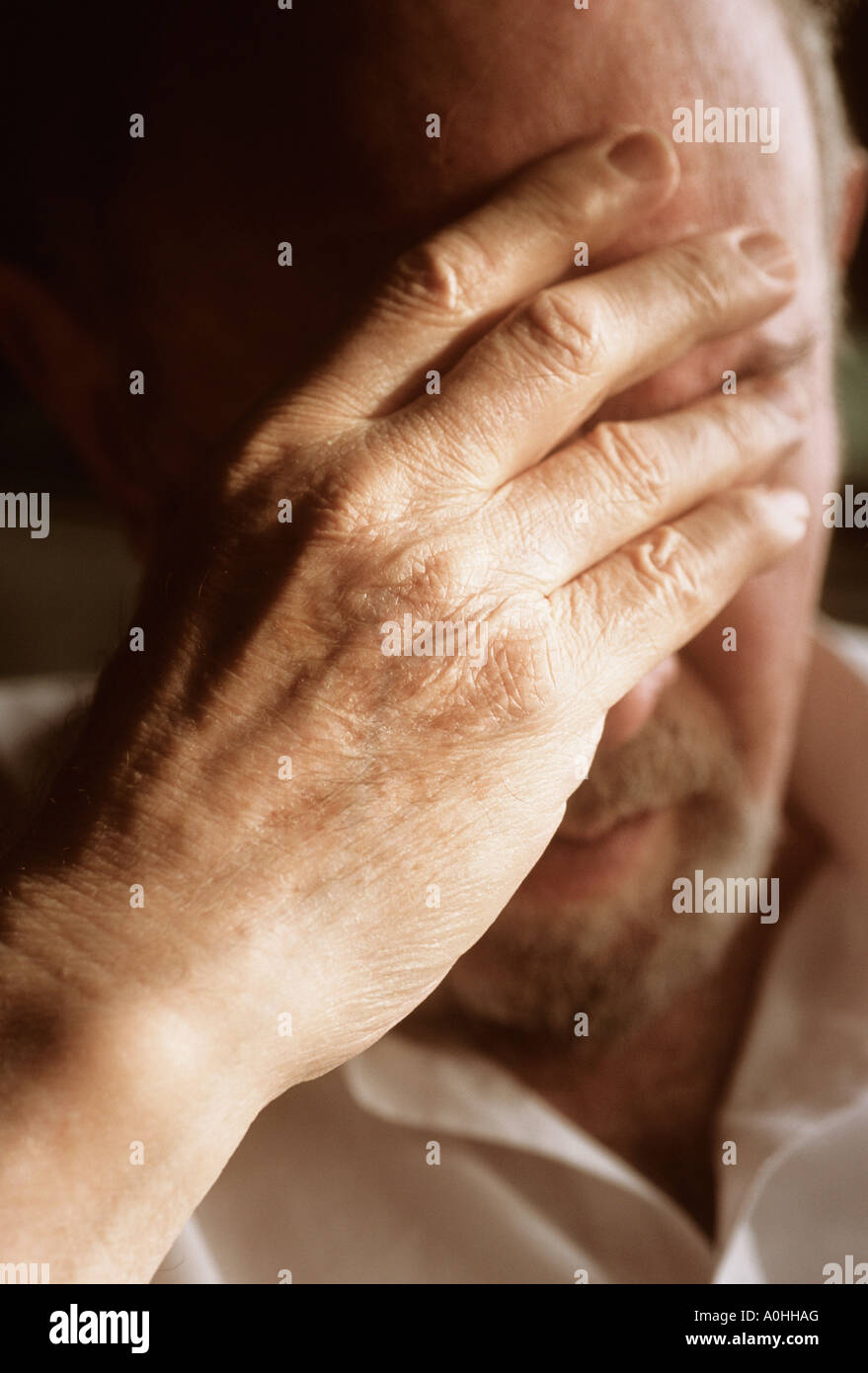 Close up of elderly man with his hand to his head. Portrait of male deep in thought. Serious, tired, depressed, worried old age pensioner. Stock Photo