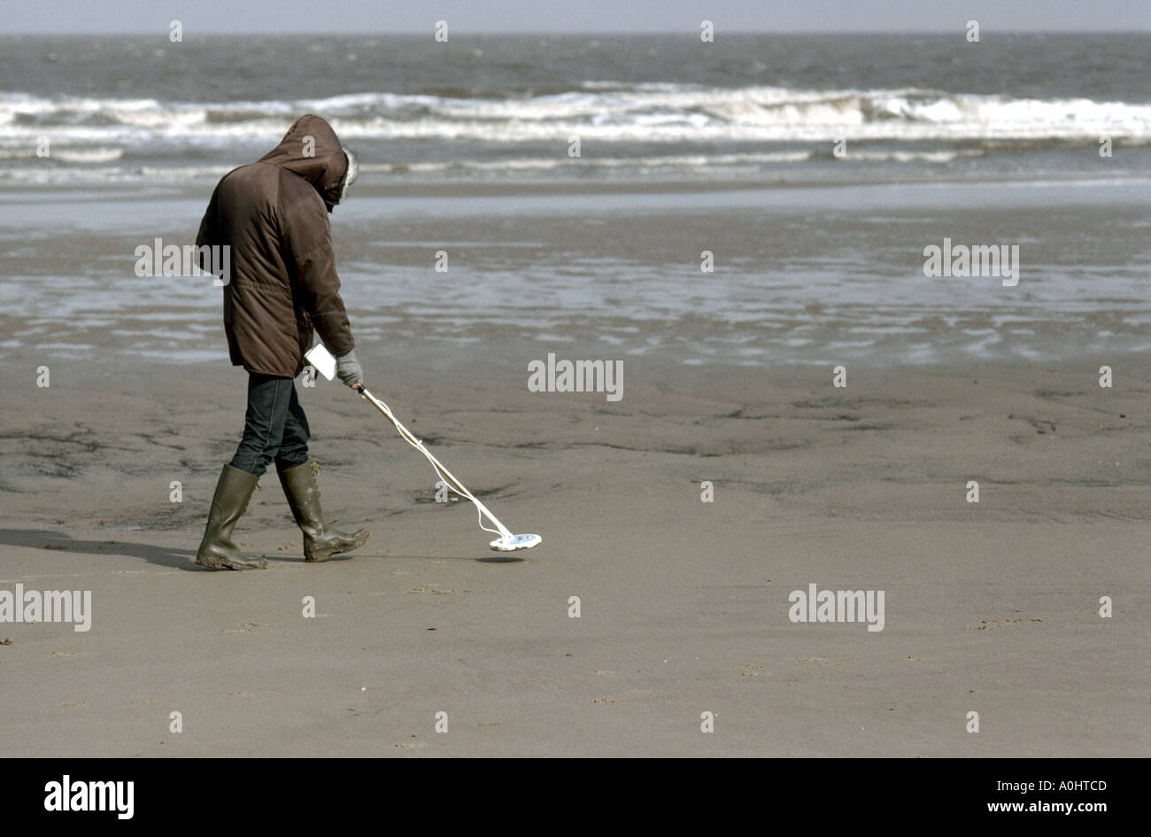 Treasure hunting with a metal detector in winter on a deserted beach of the north sea in Lincolnshire UK Stock Photo