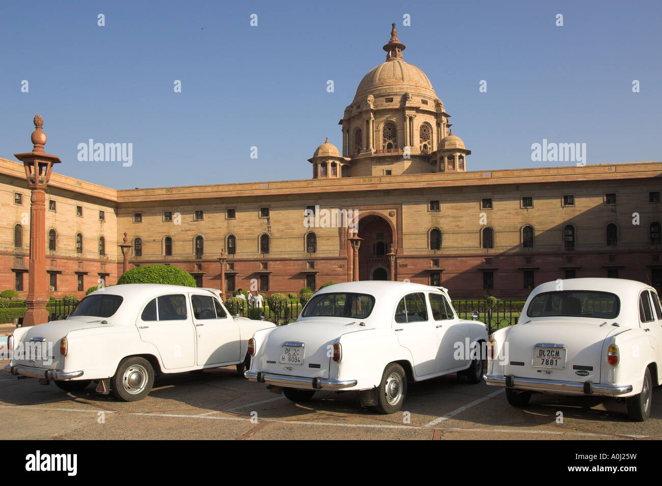 India Dehli Rashtrapati Bhavan The Secretariats view with white official ambassador cars with secretatriat in bkgd vertical Stock Photo