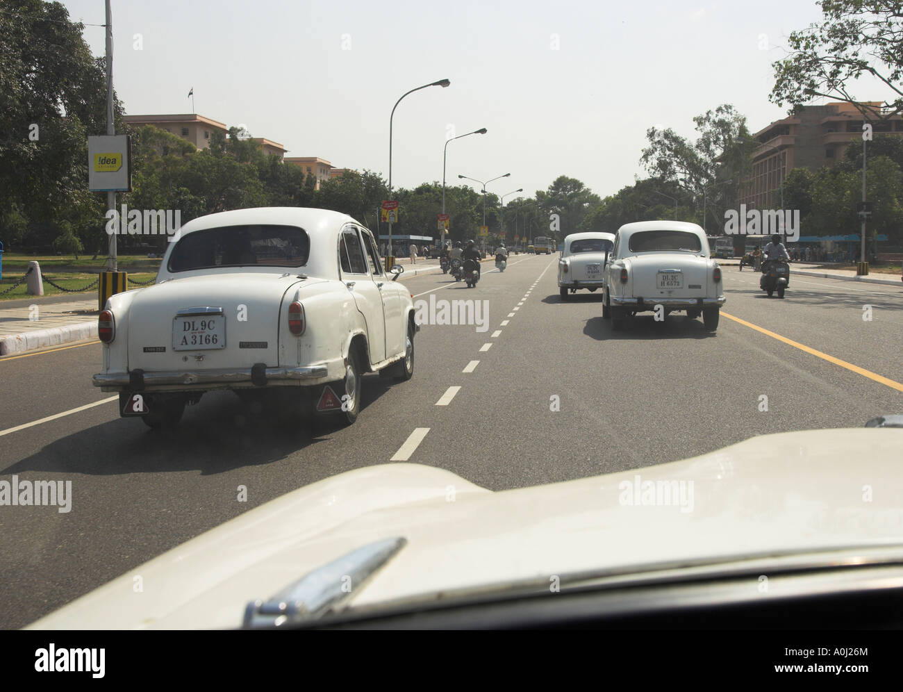 India Dehli white ambassador cars riding on new road seen through taxi windscreen Stock Photo