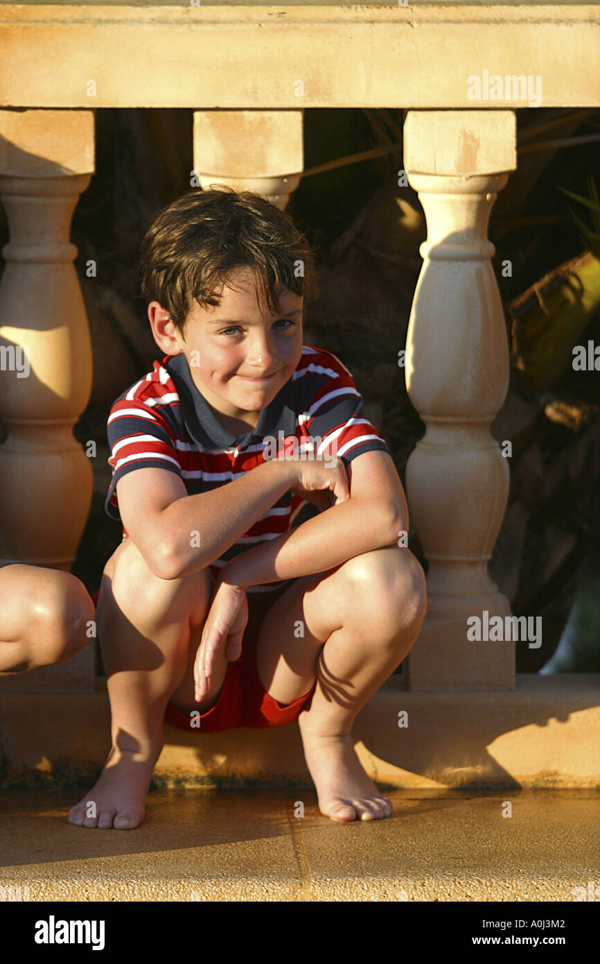 Portrait of a boy squatting in front of a banister Stock Photo - Alamy