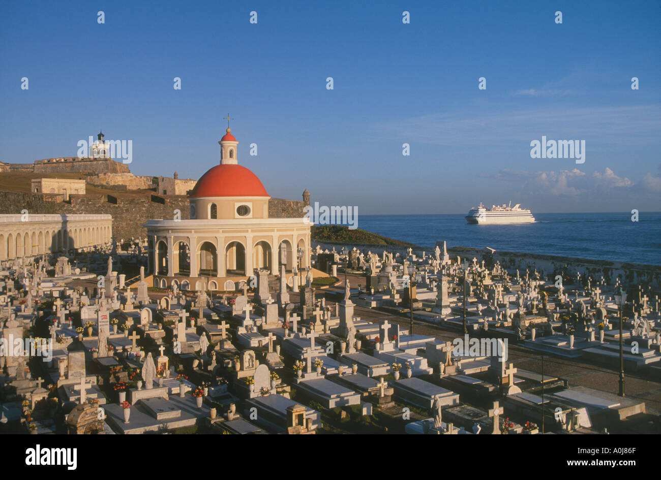 Old San Juan Puerto Rico San Juan Cemetery with El Morro lighthouse and fort behind with cruise ship approaching the island Stock Photo