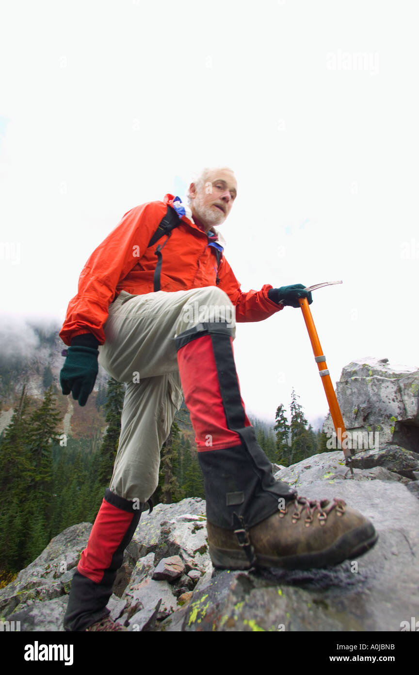 A mature man hiking on a rocky slope with a mountaineering axe Stock