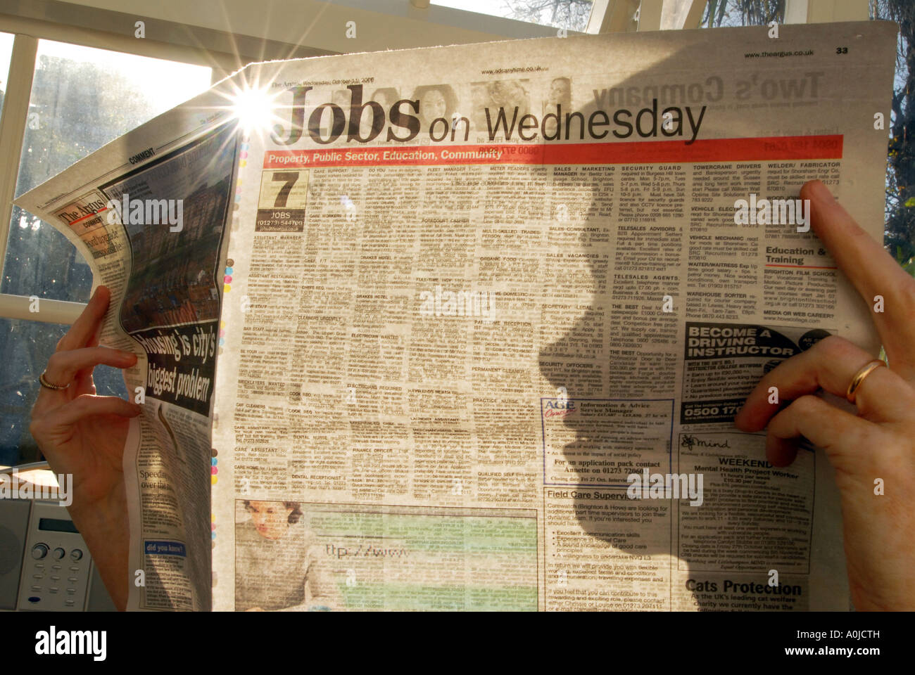 Silhouette of someone looking at job ads in a paper Stock Photo