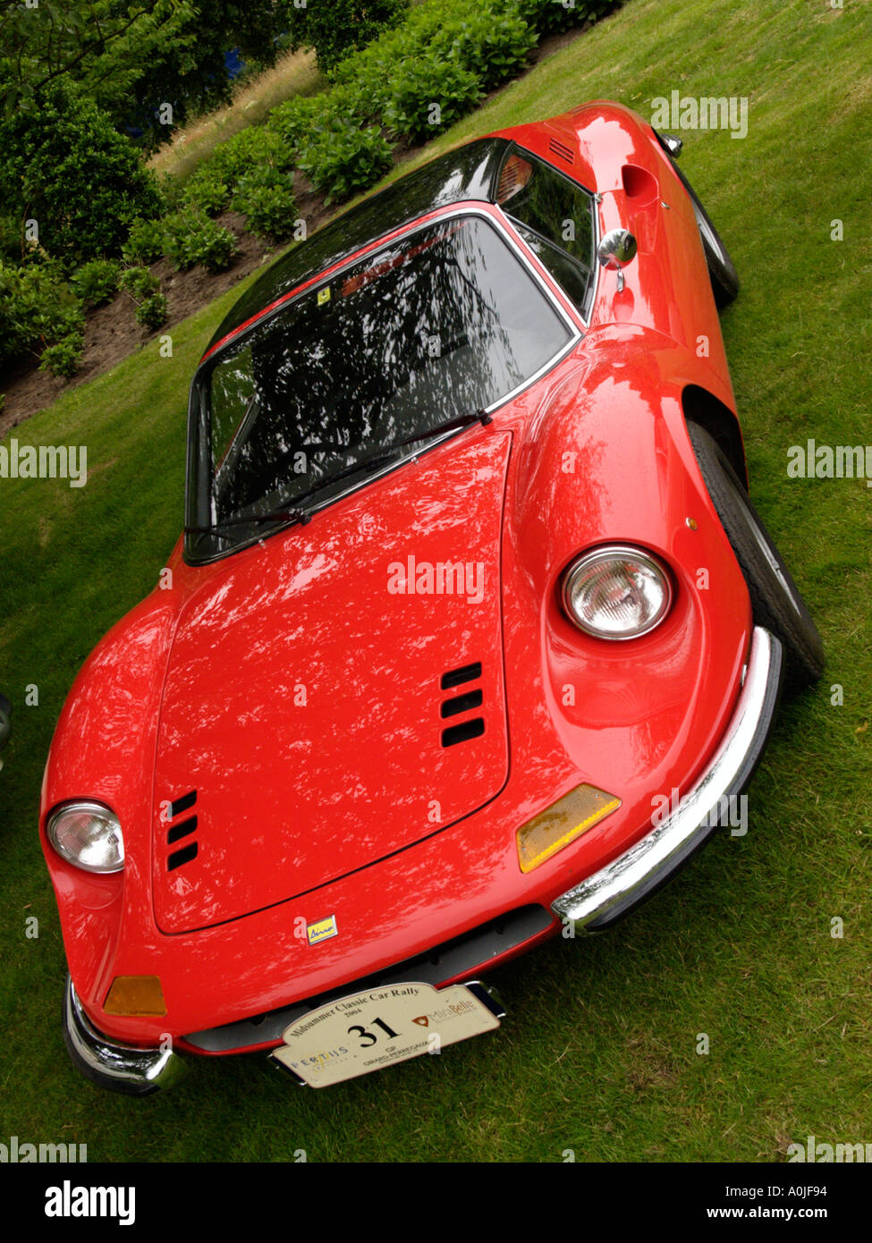 Classic bright red Ferrari Dino 246 GT parked on a grass field with rallye shield attached Stock Photo