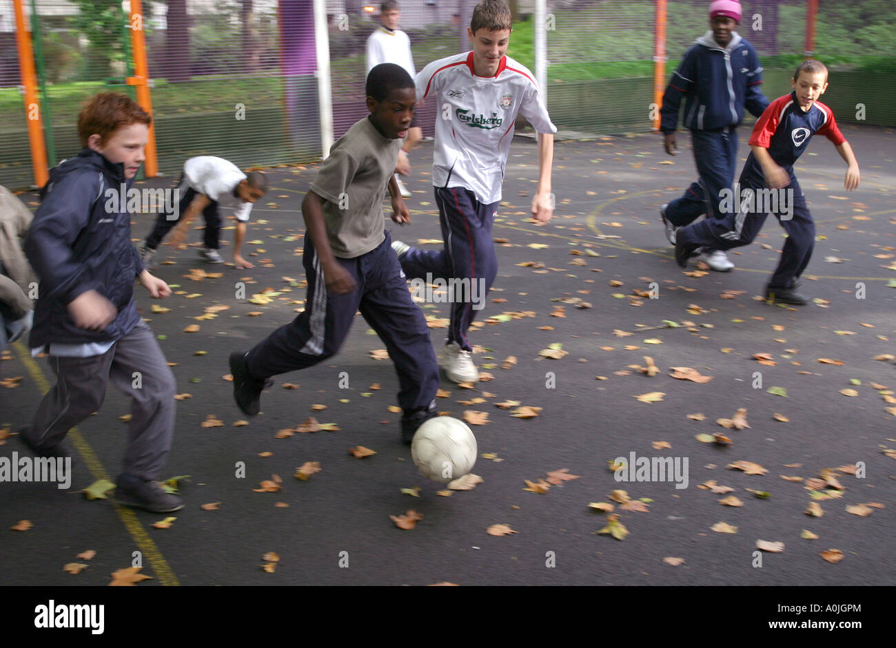 A young afro-caribbean  boy playing soccer with his friends on a housing estate. Stock Photo