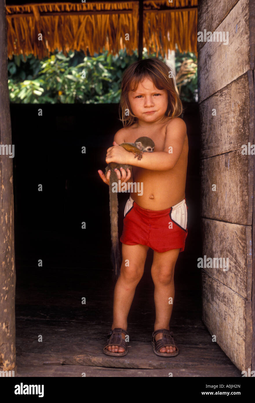 Brazilian boy holding pet squirrel monkey along Ariau River west of Manaus Amazonas State Brazil South America Stock Photo