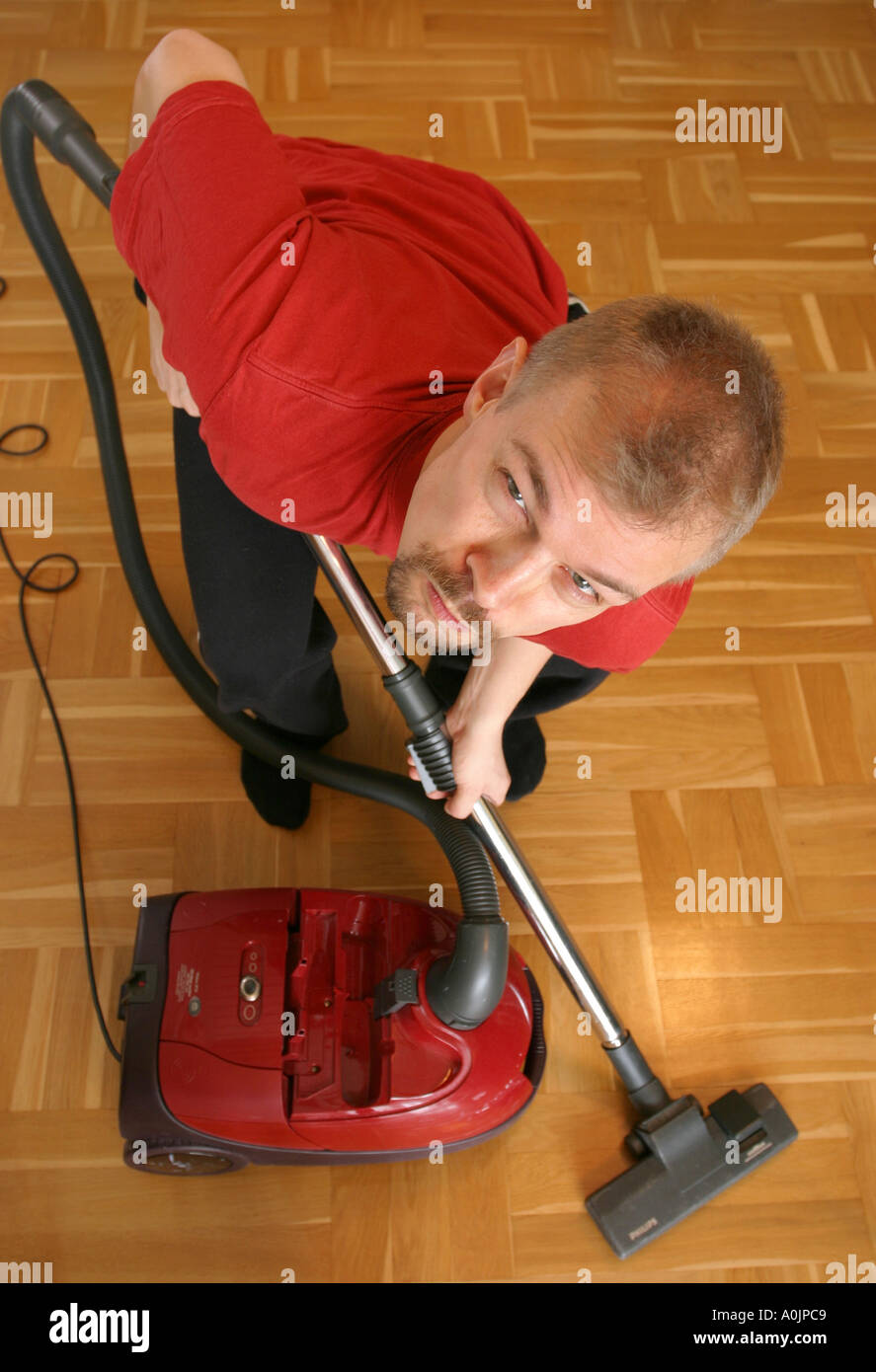 Grumpy man vacuum cleaning the floor Stock Photo