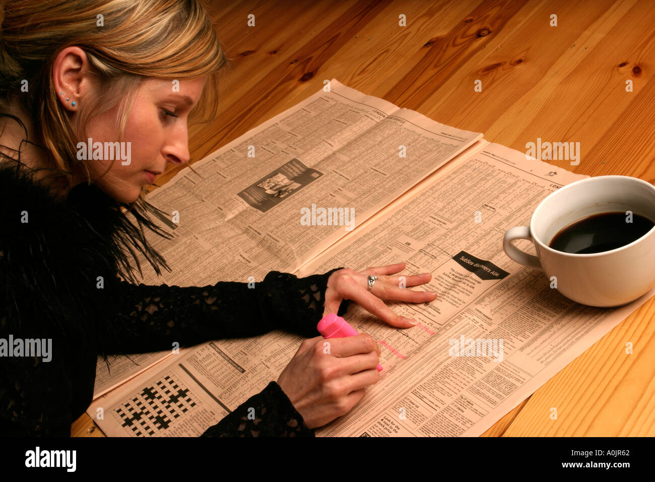 Young woman looking for stocks and shares in the Financial Times Stock Photo