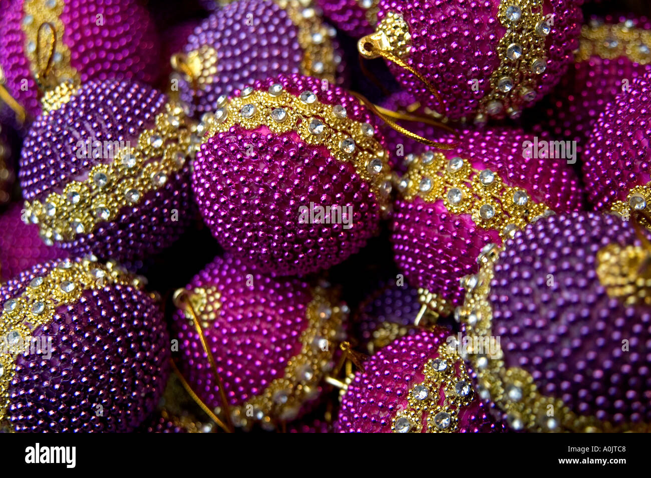 Luxurious, sparkly, purple and magenta coloured Christmas baubles. Each has a ring of faux diamonds around the edge. Shot with a narrow depth of field Stock Photo
