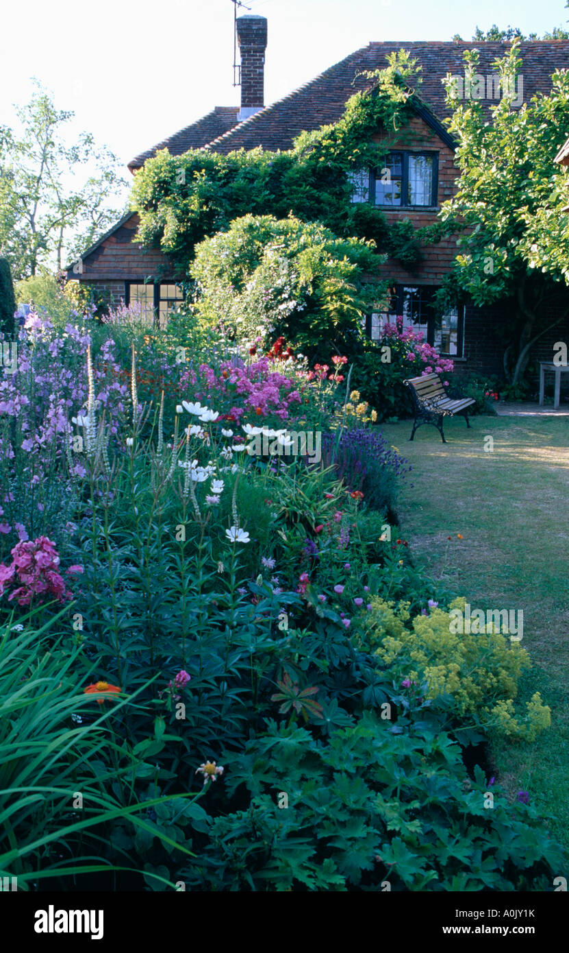 Summer Perennials In Border Beside Lawn In Front Of Country