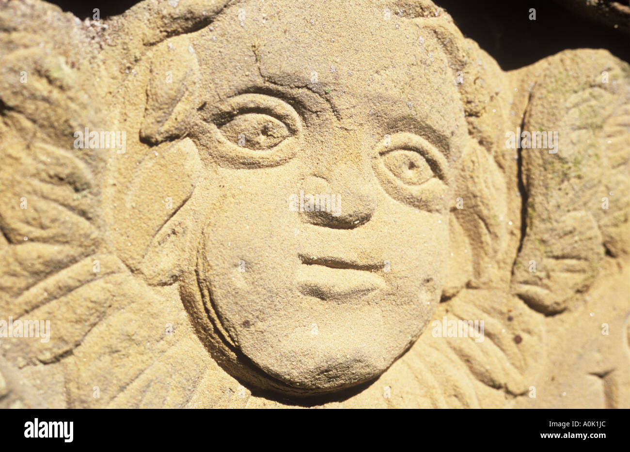 Close up detail of a naive carved face in sandstone worn and cracked through weathering Stock Photo