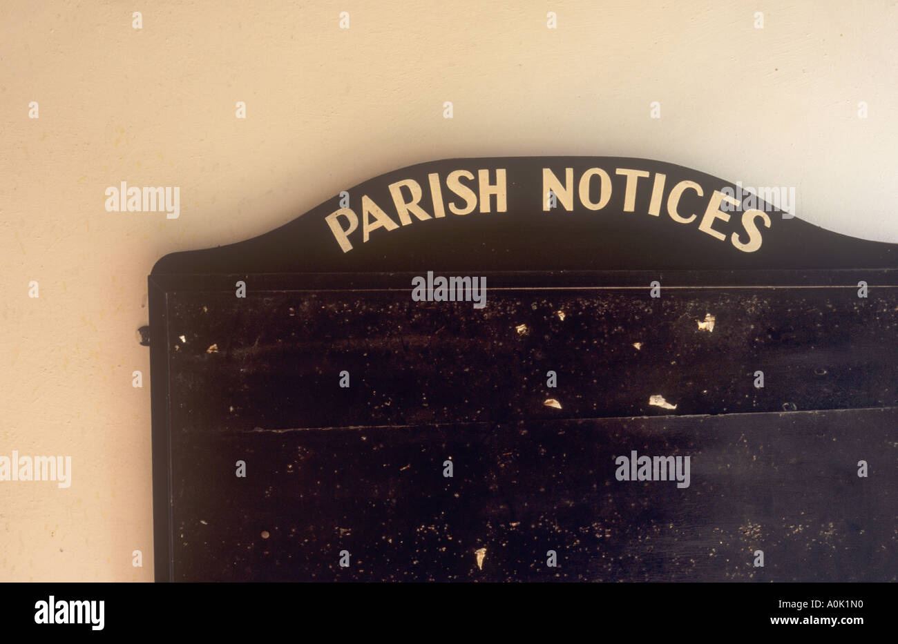 Detail of a black wooden notice board with notices removed on pale wall