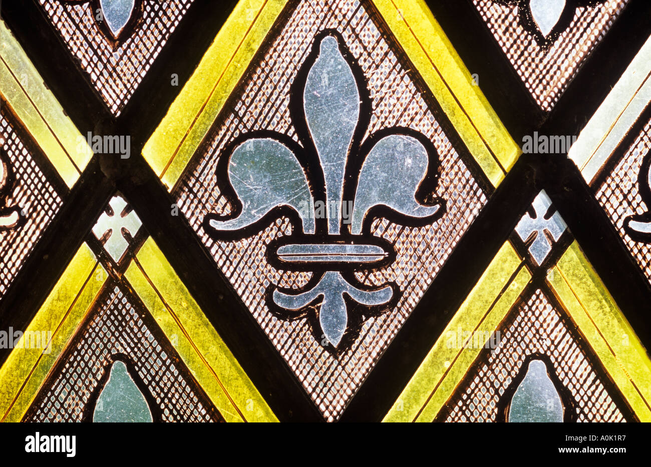 Close up straight on detail of Victorian diamond patterned stained glass with a repeating fleur-de-lys motif Stock Photo