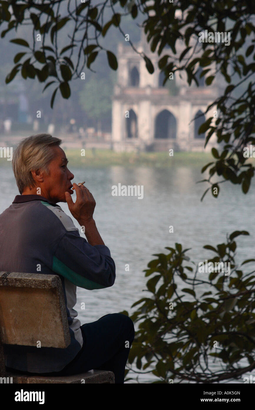 A Vietnamese man smoking beside Hoan Kiem lake in Hanoi city, Vietnam ...