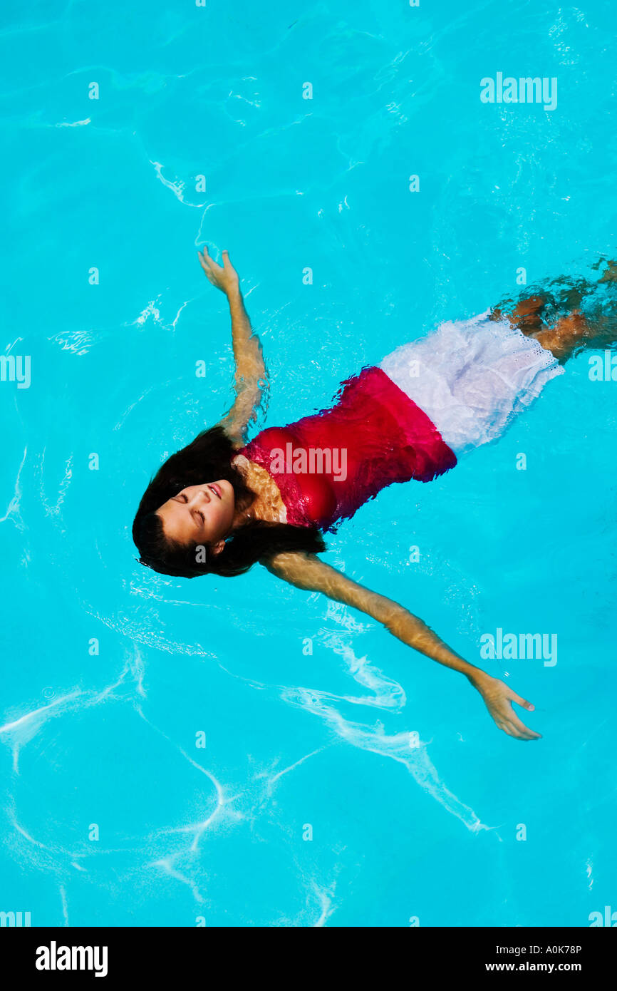 Teen girl floating in swimming pool with clothes on Stock Photo Alamy