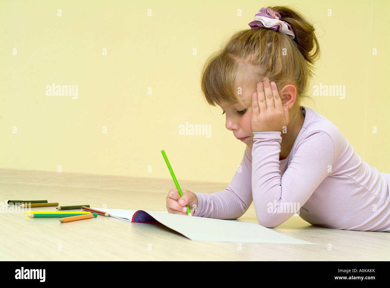 young girl using crayons in her colouring book Stock Photo