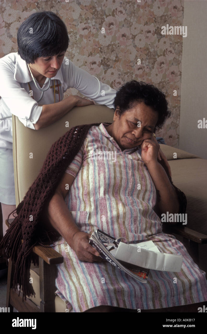 Caucasian nursing home nurse comforting depressed African American resident Stock Photo