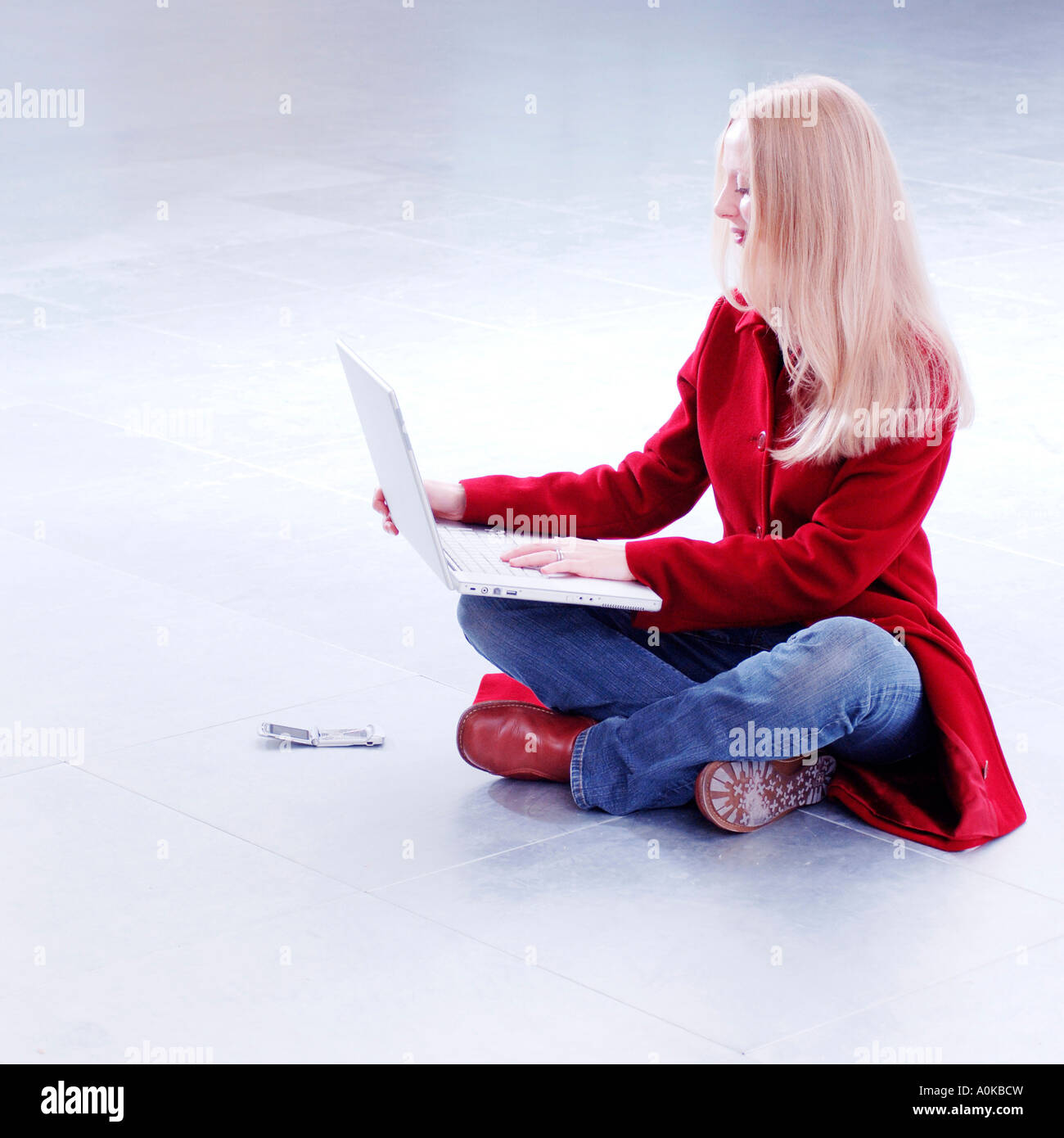 young woman sitting cross legged on floor working with notebook ...