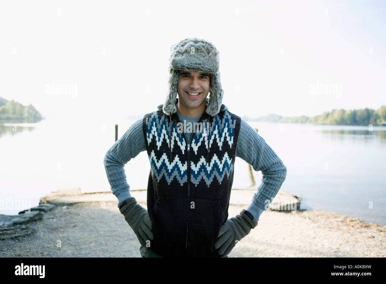 portrait of man standing at lake wearing fur hat and gloves Stock Photo