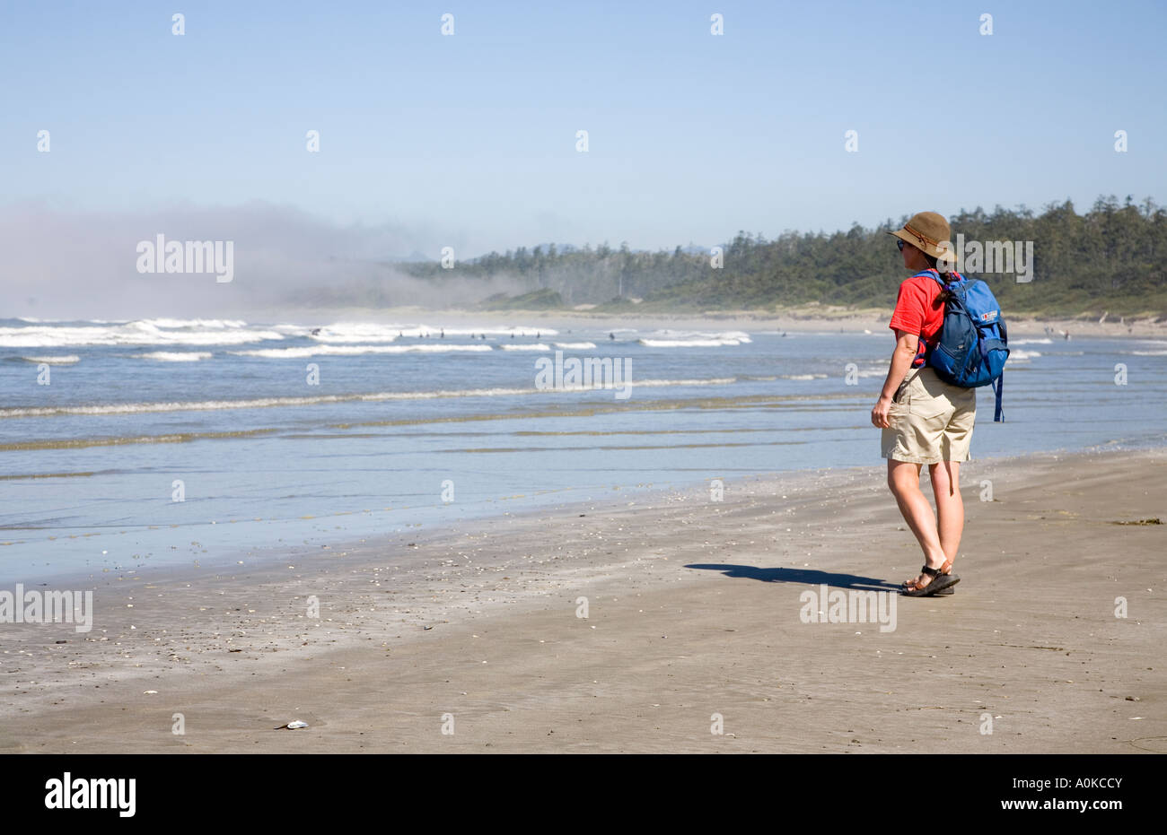 Walker looking at surfers on Wickanninish Beach west coast of Vancouver island Canada Stock Photo