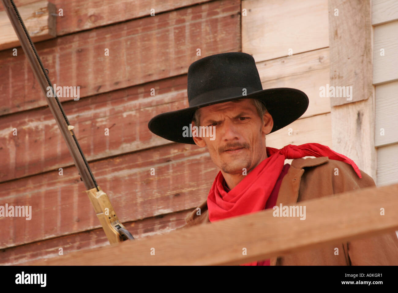 A cowboy with a gun on a balcony of old building during reenactment Stock Photo