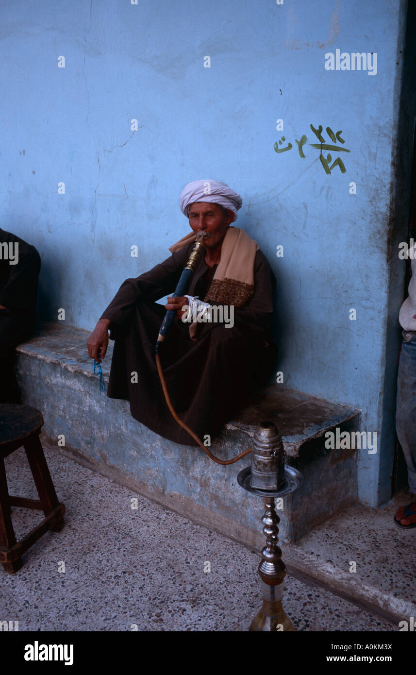 An Egyptian man smokes a hookah at a cafe in the village of Gesirat Elbaraat, on the west bank of the Nile at Luxor, Egypt Stock Photo