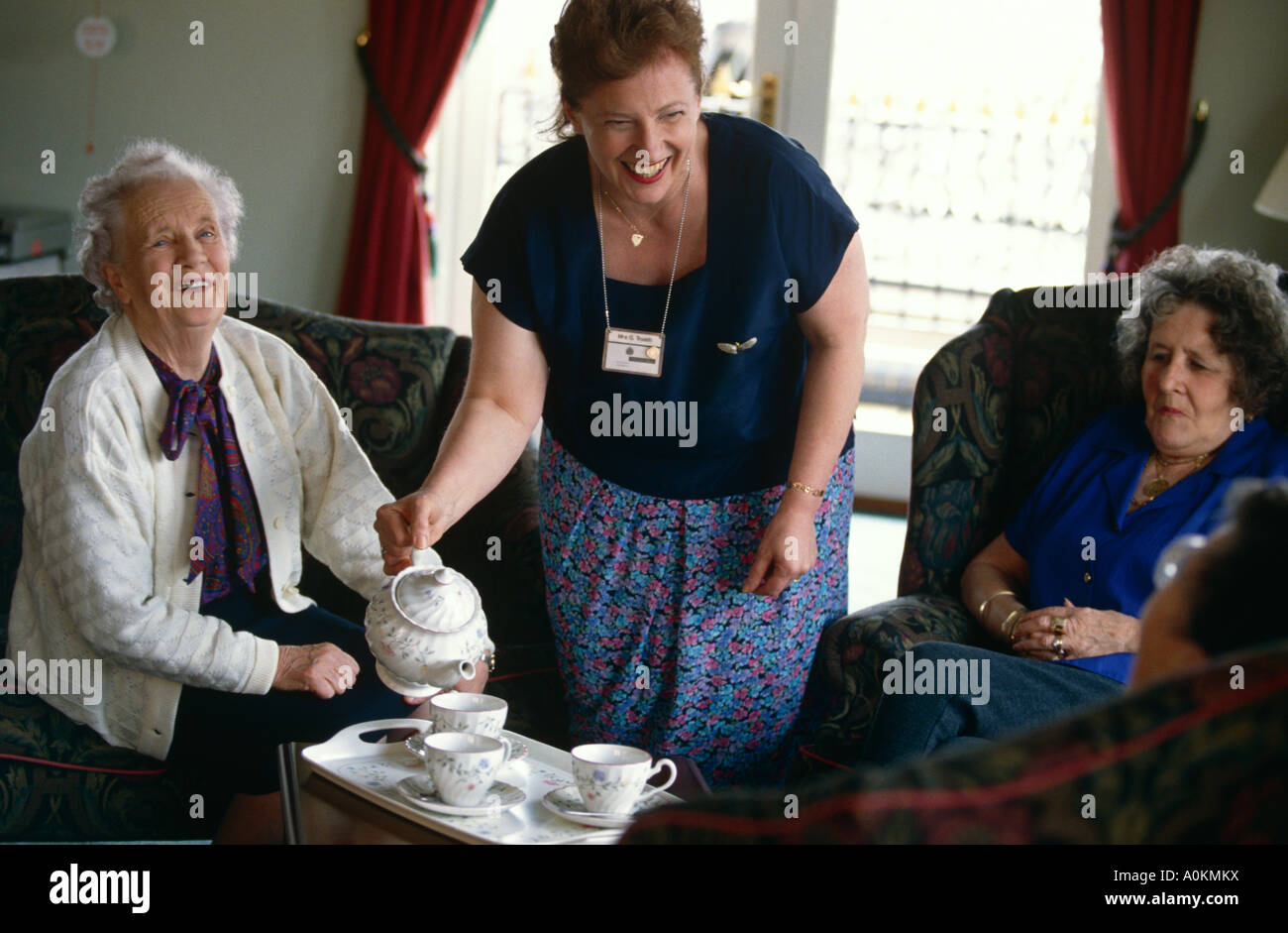 a care assistant carer pours tea for residents in an old persons people home in Braintree Essex London England GB UK Stock Photo