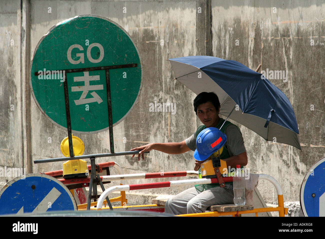 Shaded construction worker changes traffic signs, Hong Kong Stock Photo