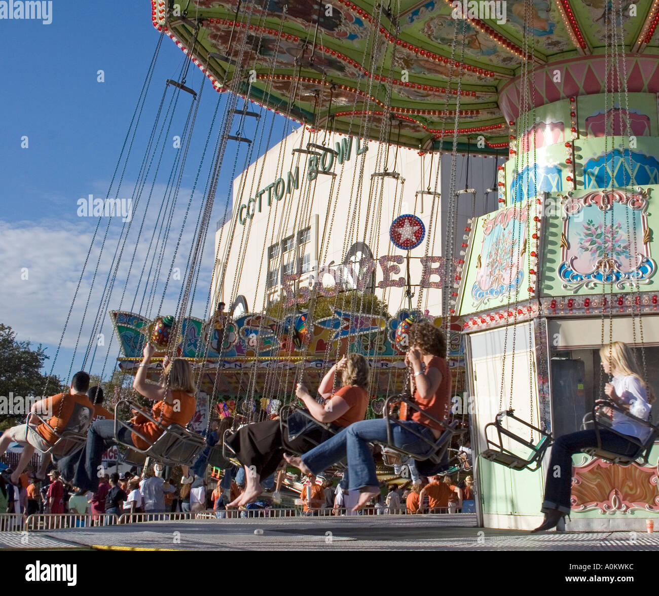 People riding the swings carnival ride in front of the cotton bowl at
