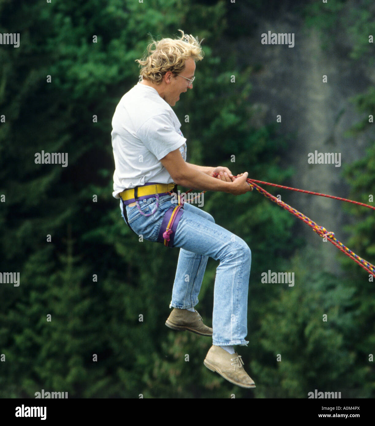 Man jumping off a bridge with a rope screaming while Bridge Diving Bungee Jumping Stock Photo