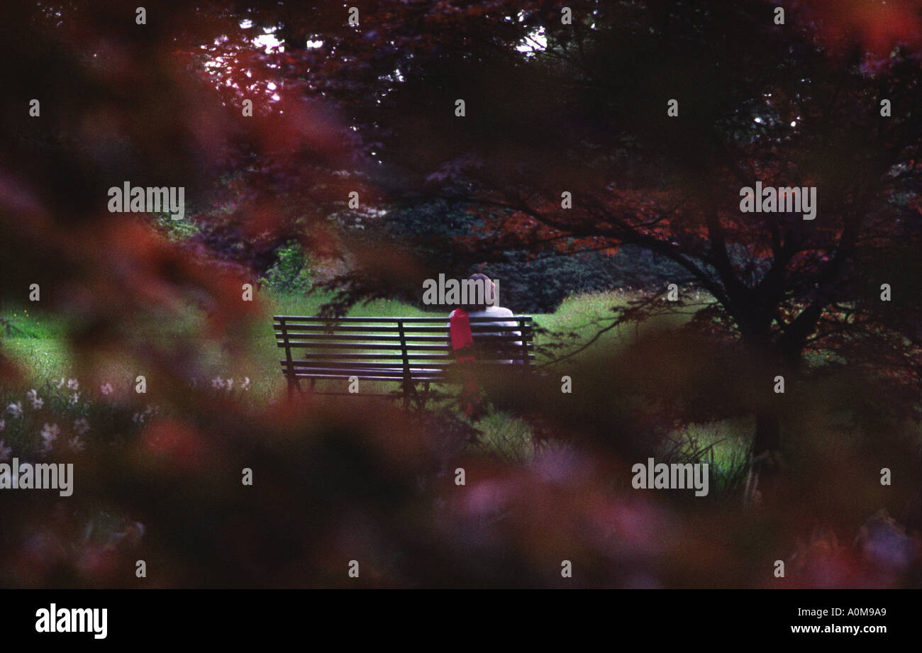 Young girl sitting alone on a park bench Stock Photo