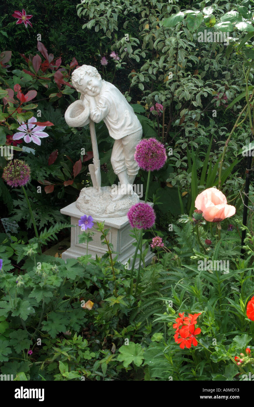 Garden ornament set amongst Poppies Perenial Geraniums Clematis Alliums and general greenery Stock Photo