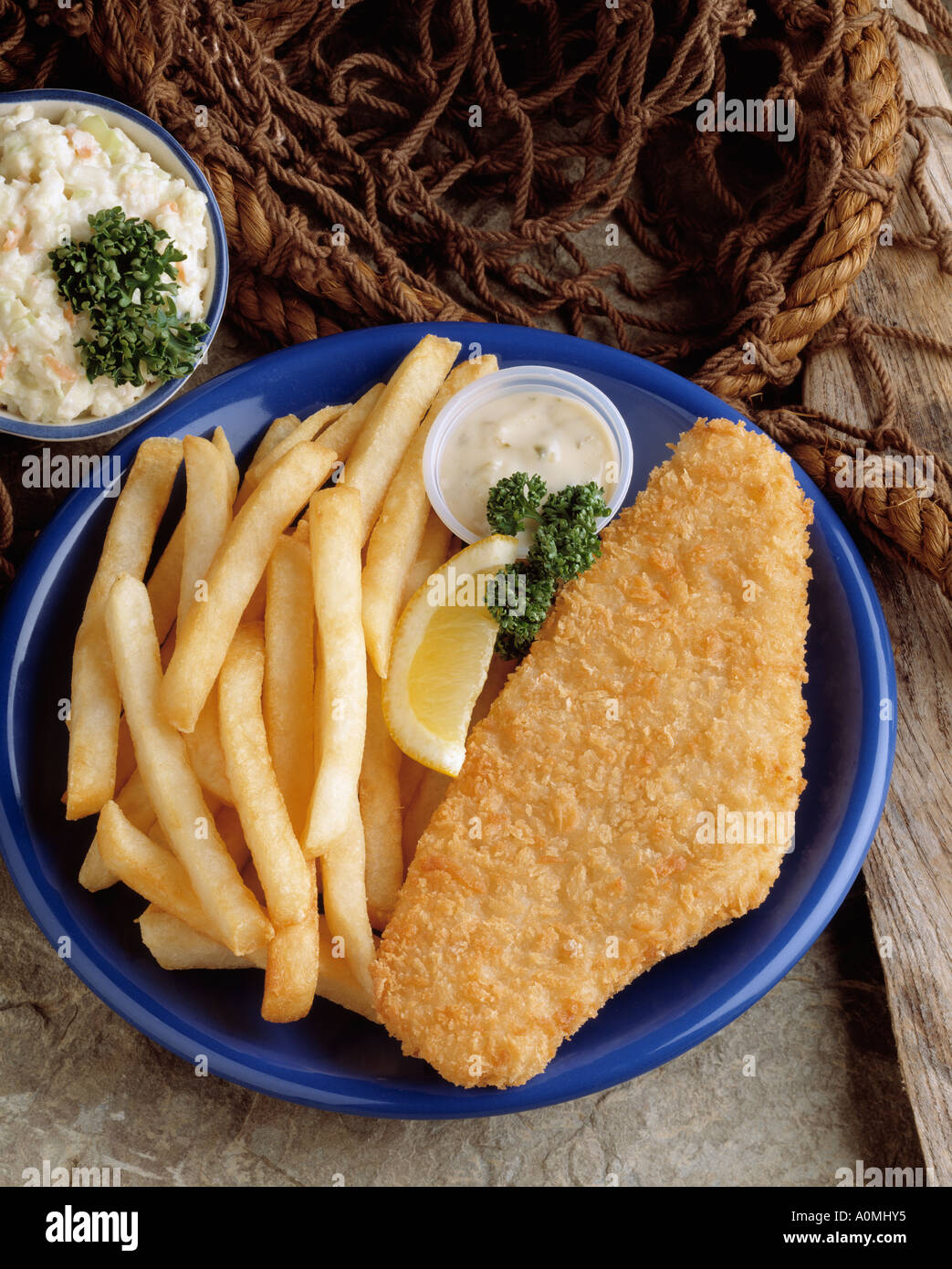 fish platter filet chips french fry fries tartar sauce cole slaw blue plate nautical prop net seafood lemon slice Bon Appetit Stock Photo