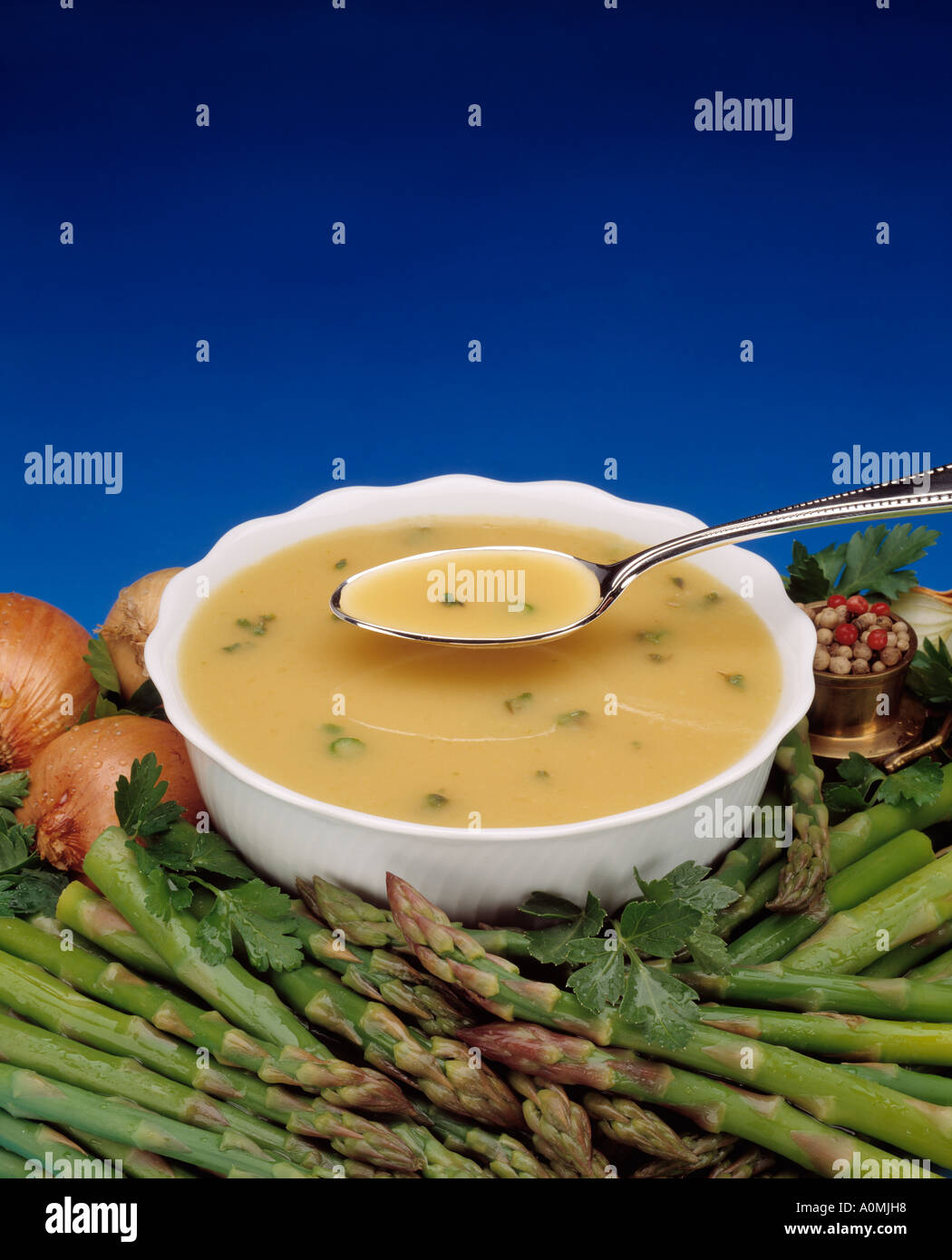 cream of asparagus cup bowl spoon onion blue background nuts spices Bon