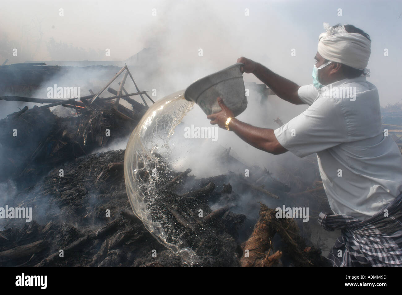 man pouring oil on funeral pyre after Tsunami earthquake Nagapattinum