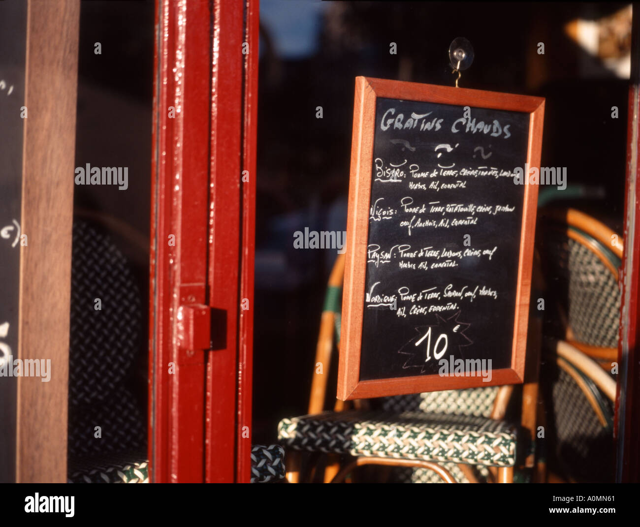 Paris, France. Chalk on blackboard menu in window of closed restaurant on Left Bank. Typical chairs stacked up inside Stock Photo