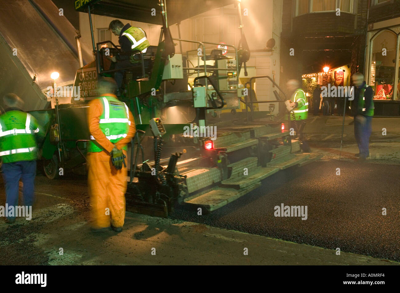 Roadworkers laying new road surface at night in Ambleside to minimise
