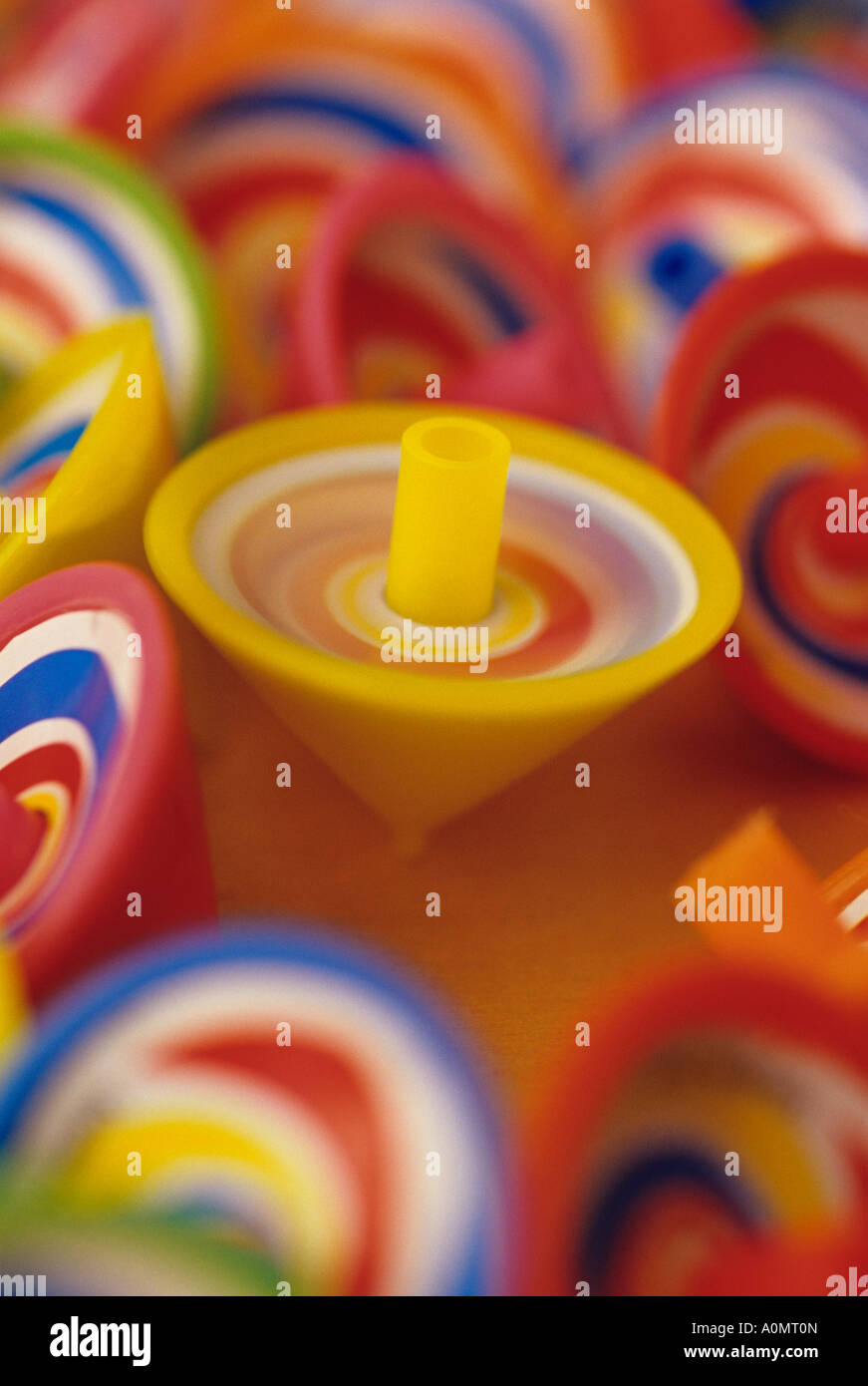 One yellow spinning top amongst a bunch of multi colored motionless