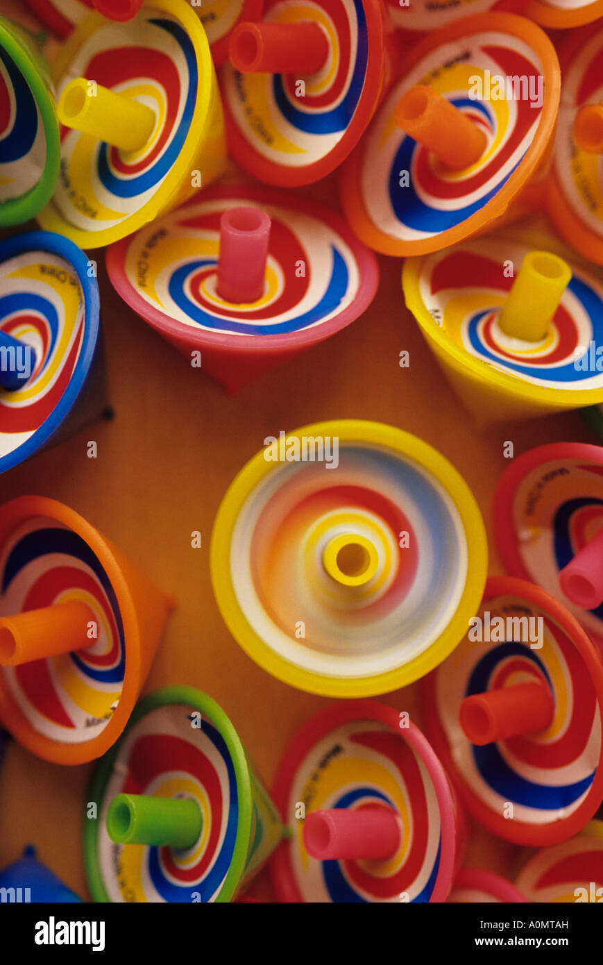 One yellow spinning top among other motionless multicolored spinning