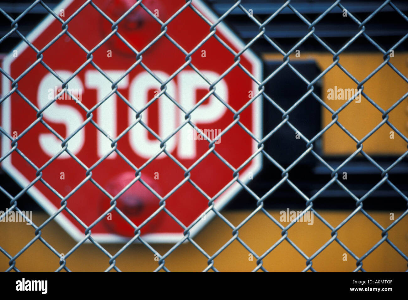 yellow school bus red stop sign chain link fence Stock Photo