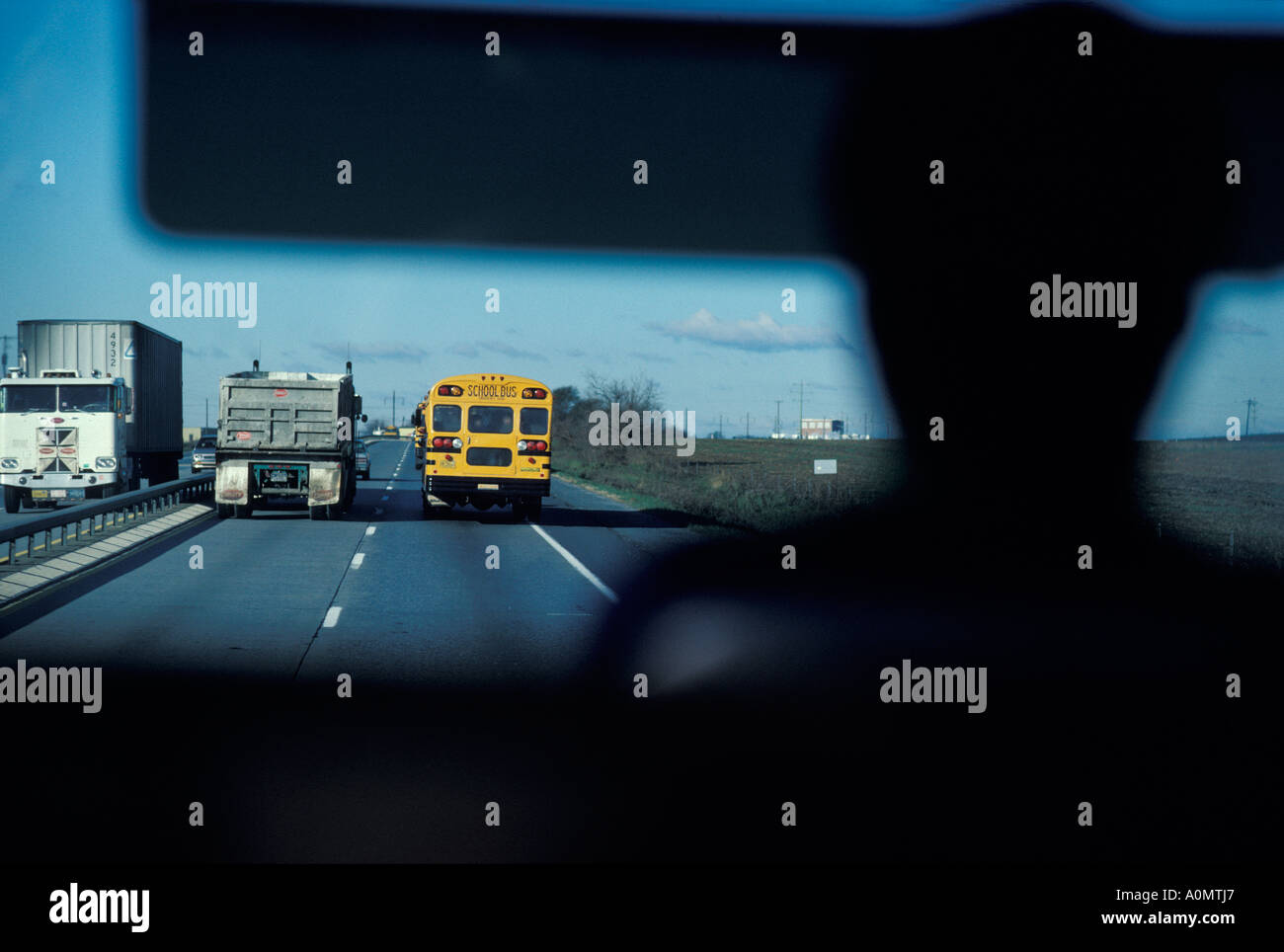 yellow school bus drivers view silhouette trucks highway passing lane danger Stock Photo