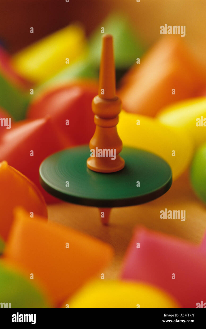 One old wooden spinning top spinning among motionless colorful upside