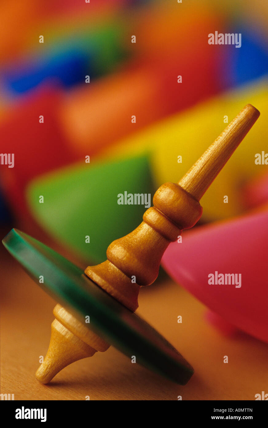 One old wooden spinning top motionless among other upside down colorful