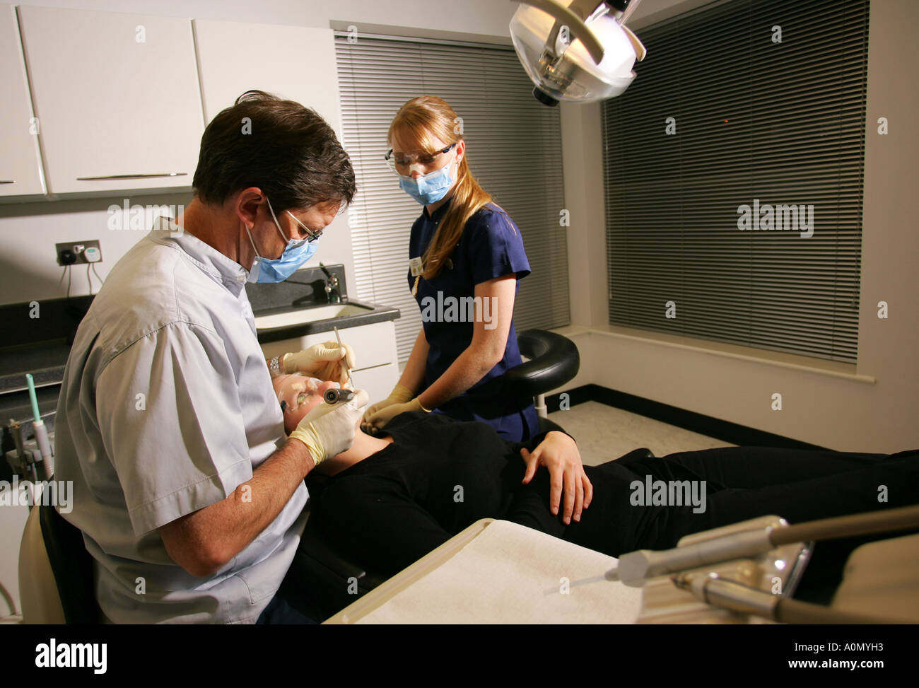 Teeth and gum treatment by a dentist and his assistant on a patient in