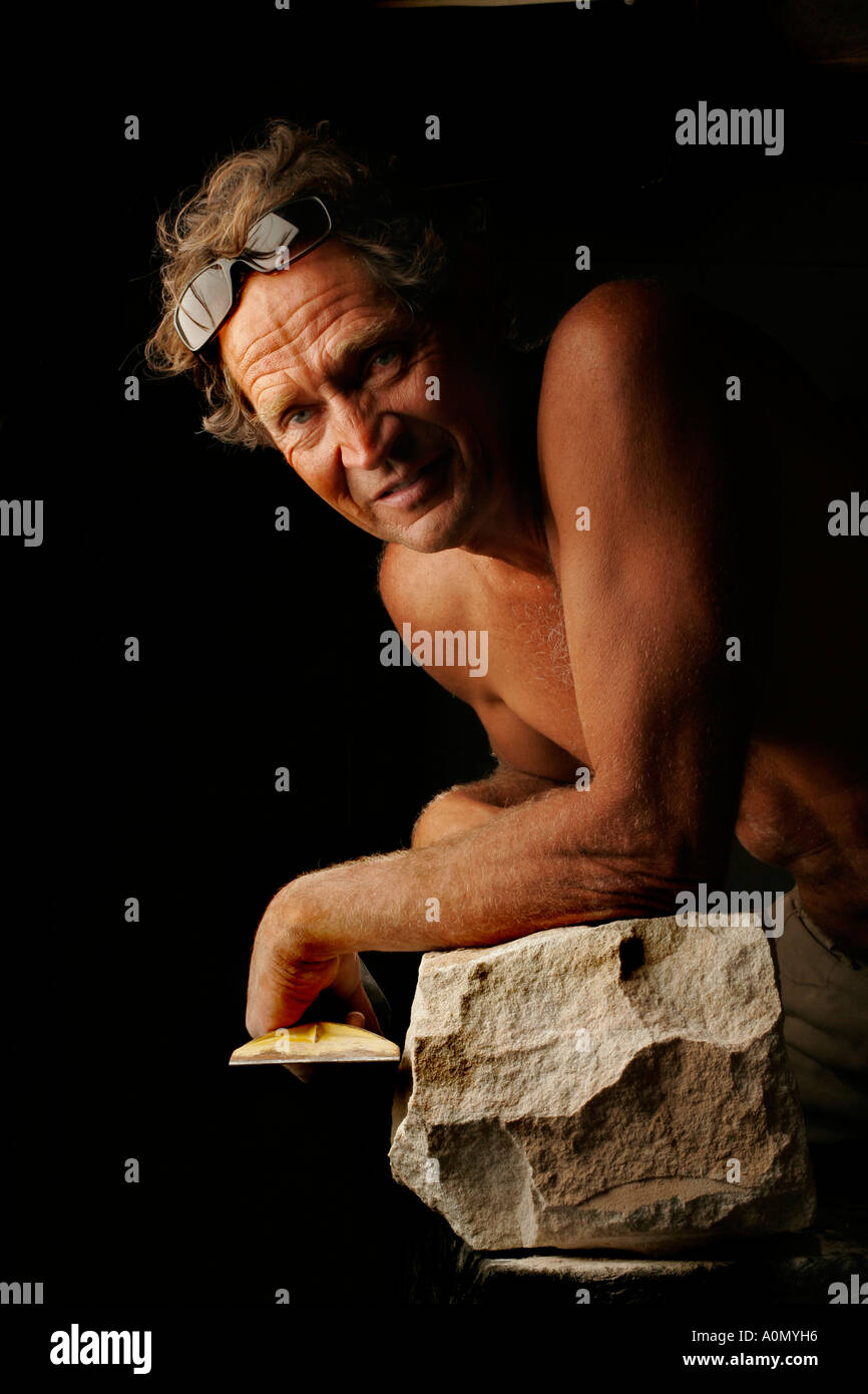 A stonemason works with hammer and cold chisel in studio light Stock Photo