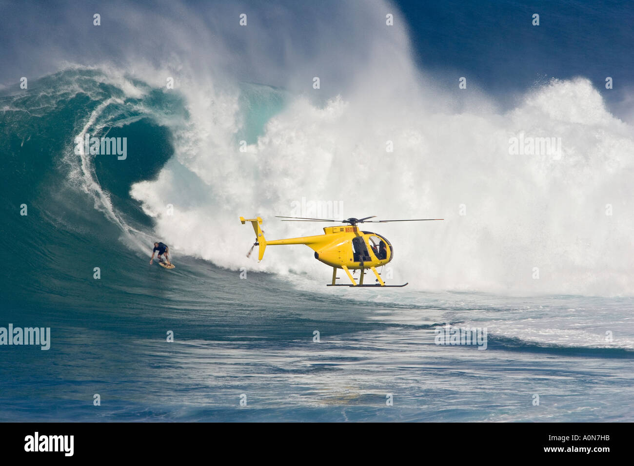 A helicopter filming tow in surfer, Laird Hamilton at Peahi, (Jaws) off Maui, Hawaii. Stock Photo