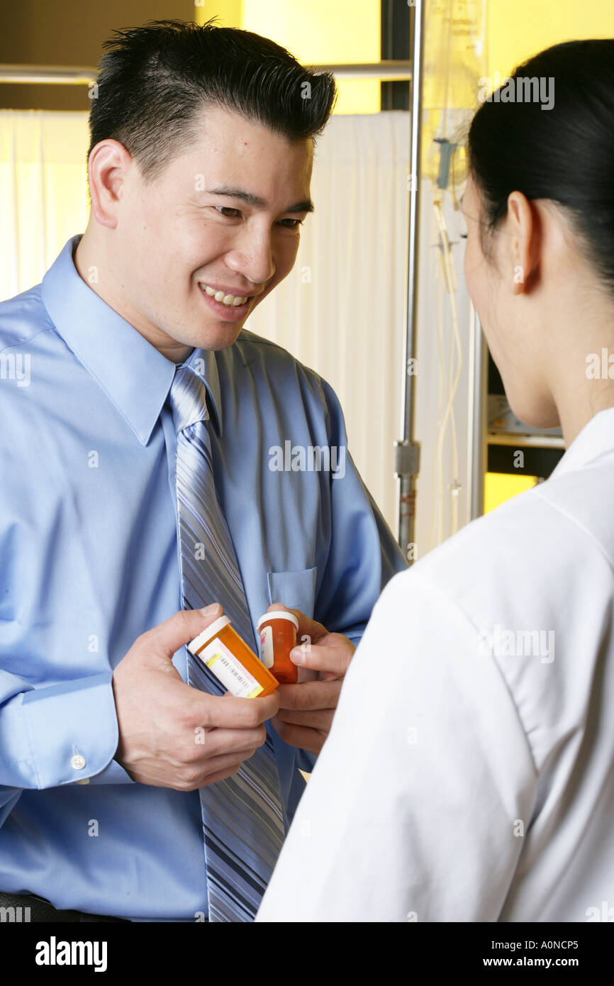 Asian male patient receives drugs from female doctor. Stock Photo