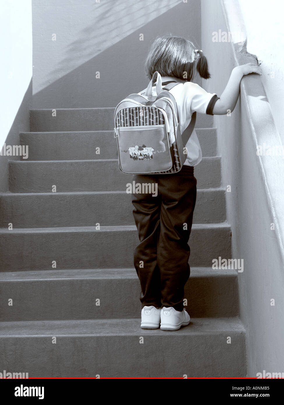 Infant school girl pauses insecure anxious on school steps unsure of her situation Black and White Stock Photo